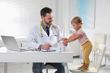 Wall Mural - Pediatrician playing with cute baby in clinic