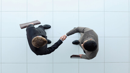 Business partners shaking hands as a symbol of unity, view from the top