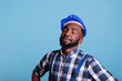 © DC Studio - Construction worker with a dream to start work very early in the morning. African american contractor wearing hard hat and work uniform with eyes closed. against blue background, studio shot.