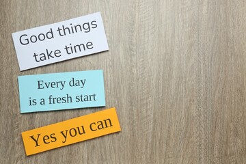 Wall Mural - Notes with motivational quotes on wooden background, flat lay. Space for text