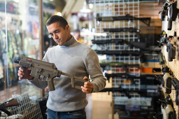 Wall Mural - European man holding machine gun in air weapon shop.