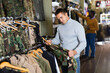 © JackF - Positive guy choosing camouflage uniform in military shop