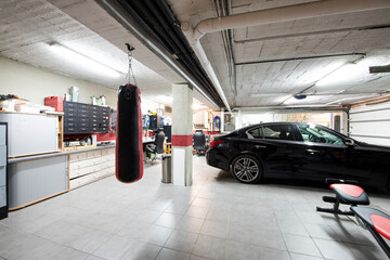 A detached house garage with gray floors, a punching bag and a parked luxury vehicle