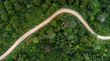 Fototapeta Uliczki - Aerial view from drone of mountain road with sun shining in forest. Top view of a road on a hill in a beautiful lush green forest in Thailand. Natural landscape background.