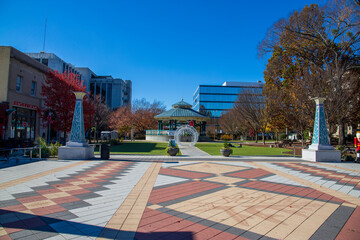 Wall Mural - a gorgeous autumn landscape at the Decatur Square with red and yellow autumn trees, lush green trees and a round blue pergola, glass office buildings and clear blue sky in Decatur Georgia USA