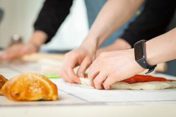 Wall Mural - Close-up on cooks hands, cooking bakery in a bright kitchen by two chefs, selective soft focus.