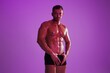 © SHOTPRIME STUDIO - Man athletic body bodybuilder in briefs with nude torso abs full-length in the background fitness classes, purple colored light. Advertising, sports, active lifestyle, competition, challenge concept.