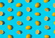 Summer pattern made with fresh cut and whole yellow lemon on bright light blue background. Minimal background summer concept on with harsh light and sharp shadow
