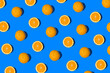 Summer flat lay pattern made with fresh whole orange fruit and slices on vibrant blue background. Minimal sunlight concept with sharp shadows