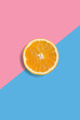 Minimalistic summer fruit tropical composition. Half of juicy fresh orange on light pastel pink and blue background. Citrus fruit refreshment. Vitamins, fresh healthy food concept. Copy space