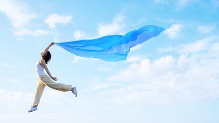 布を羽ばたかせ軽やかに空を飛ぶ女性