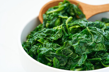 Wall Mural - close up green cook leaf spinach salad in white bowl on white table background. leaves spinach or heap of spinach food salad                                                                      