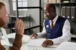 © Mediaphotos - Portrait of senior black man as attorney working with client in office and looking at legal documents