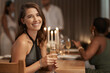 © N F/peopleimages.com - Party, celebration and portrait of a woman with champagne at a new year dinner at restaurant. Happy, smile and lady sitting at dining table with glass of wine to celebrate at festive event at a house