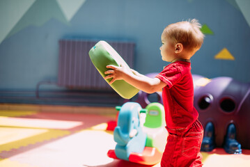 Happy laughing boy 1-2 years old having fun in ball pit  in kids amusement park and indoor play center. Activity toys for little kid