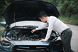 Asian businessman car broken breakdown, young stressed man having trouble car failure problem looking in frustration at failed engine in the morning, accident on road outdoor, late for work