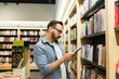 © AntonioDiaz - Thoughtful young man choosing to buy a book at the shop