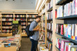 © AntonioDiaz - Caucasian man with a backpack browsing the bookshelves at the store