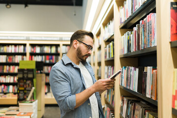 Thoughtful young man choosing to buy a book at the shop