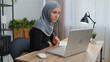 © Andrii Iemelianenko - Muslim business woman in hijab study with notebook at home office on laptop computer making conference video call talking to webcam. Online teacher e-learning in remote chat. Distance education online