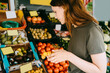 © Maskot - Side view of female customer buying fruits at market