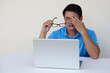 Asian man, feels hurt his eyes, holds eyeglasses during working on laptop. concept : Eyesight problem. Optometry. Glasses with convex or concave lenses. Myopia.Eye disease         