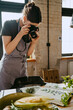 © Maskot - Food stylist photographing through digital camera while working in studio