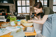 © Maskot - Female food stylist with digital camera setting up vegetable bowl on table in studio