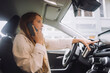 © Maskot - Female entrepreneur talking through mobile phone while using touch screen control panel on dashboard in car