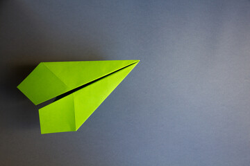 Wall Mural - green paper plane origami isolated on a grey background
