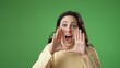 © Robert Peak - Portrait of happy young woman 20s smiling scream and shout calling inviting with hands at mouth say hey you isolated on green screen background.