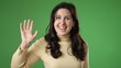 © Robert Peak - Waving to friend meet greet, portrait of happy smiling young woman 20s isolated on green screen background.