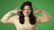 © Robert Peak - Displeased irritated frustrated sad angry young brunette woman 20s years closed eyes cover ears do not want to listen scream isolated on green screen background studio portrait