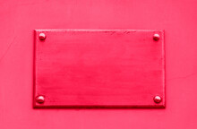 Old Metal Plate Framed And Nailed On Stucco Wall Outdoor Background. Image Toned In Trendy Color Of Year 2023 Viva Magenta.