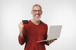 © InsideCreativeHouse - Smiling caucasian middle-aged mature businessman bank employee client customer holding credit card and laptop for online shopping e-banking e-commerce isolated in white background