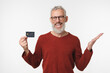 © InsideCreativeHouse - Happy middle-aged mature with grey hair businessman bank employee worker manager client customer holding credit card for e-banking e-commerce cashless payment isolated in white background