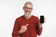 © InsideCreativeHouse - Positive caucasian mature middle-aged freelancer man pointing at mockup screen of cellphone smart phone, showing copy space place, mobile application online isolated in white background