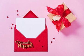 Wall Mural - Greeting card mockup, white blank card in envelope and gift box on pink background.