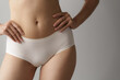 © Phushutter - Close up asian female body wearing white high-waist panties over grey background.