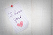 I love you note on tablet paper pinned to a white wall