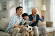 © imtmphoto - asian son father grandfather watching soccer game on TV together at home