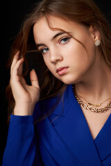 Poster - caucasian girl with long hair in a blue dress straightens her hair on a black background