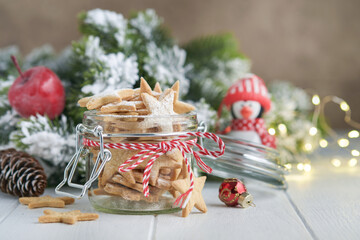 Wall Mural - Christmas shortbread cookies or gingerbread stars with red ribbon, festive decoration, fir tree,balls and light garland. Traditional german cookies. Christmas celebration traditions family culinary.