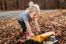 Happy Child Playing In Fall Leaves With Toy Truck