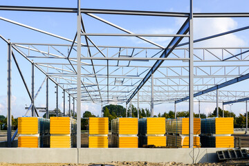 Canvas Print - Assembled steel structure and stacks of sandwich panels for the facade of a new industrial building