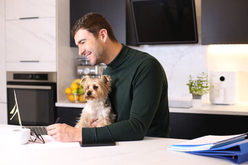 Attractive man working from home with his lap dog