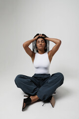 African American young woman with long braids, sitting on the floor. Mock-up.