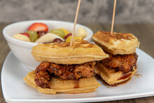 Perfectly Fried Chicken And Waffles Portioned In Halves And Served With A Bowl Of Fresh Fruit