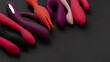 Sex toys and masturbation device. A pink, red, purple and black rubber and silicone dildos is lying on dark paper. View from above. Place for text. Flat lay. Sex shop concept