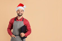 Handsome Male Waiter In Santa Hat On Beige Background